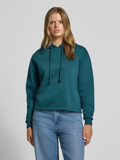 Frauenmodel trägt Regular Fit Hoodie aus Baumwoll-Mix Modell 'CHILLI' von PIECES in Dunkelgrün, kombiniert mit blauer Jeans, Ganzkörperansicht von vorne. Damen Hoodie von PIECES.