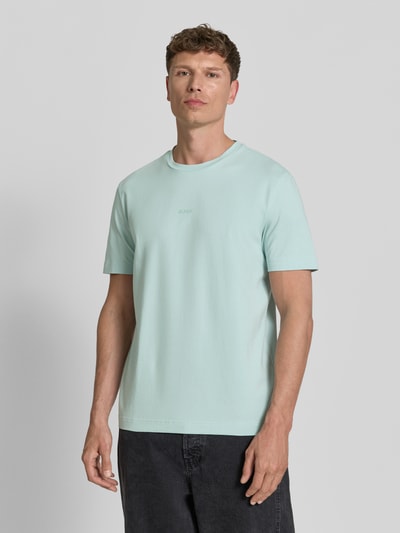 Männermodel trägt Relaxed Fit T-Shirt aus Baumwoll-Mix Modell 'TCHUP' von BOSS Orange in Uni-Optik, Label Print, Jersey-Textur, Ganzkörperansicht von vorne.