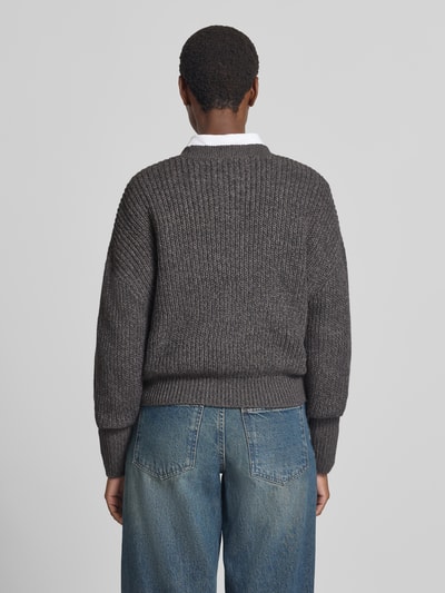 Männermodel trägt grauen kardigan rozpinany mit dekolt w serek, model 'LEA' von VERO MODA, strukturierte Stricktextur, Ganzkörperansicht Rückansicht.