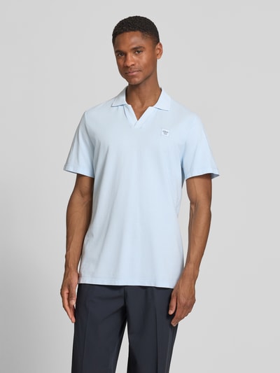 Męski model nosi Regular Fit Poloshirt aus reiner Baumwolle od s.Oliver RED LABEL, jasnoniebieski, bawełna pique, krótki rękaw, detal z logo, klasyczny kołnierzyk polo, widok całej sylwetki z przodu.