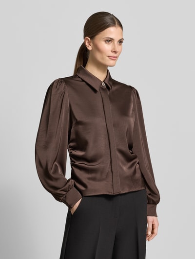 Modelka nosi Regular Fit Hemdbluse mit Raffungen Modell 'Fransala' od Neo Noir w kolorze brązowym, długi rękaw, elegancka tekstura, widok z przodu – z kontekstem: damska koszula z elastycznej mieszanki materiałów, kołnierzyk koszulowy, zdobienia z kamieni, wykończone mankiety, długość tyłu w rozmiarze 36: 55 cm, długość rękawa w rozmiarze 36: 65 cm, krój regular fit, Neo Noir.