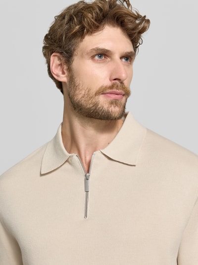 Männermodel trägt Relaxed Fit Pullover aus reiner Viskose Modell 'TELLER' von Selected in beige, structuurpatroon, polokraag, fijngebreid materiaal, Nahaufnahme Oberkörper.