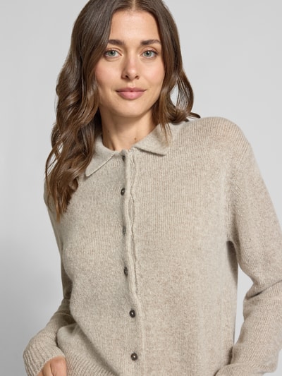 Vrouwenmodel draagt Strickjacke aus Kaschmir-Mix mit Lanawoll-Anteil Modell 'Gina' van 0039 Italy, beige, regular fit, geribde boorden, lange mouw, knoopsluiting, kraag, close-up bovenlichaam.