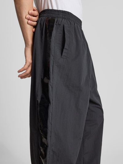 Männermodel trägt Sweatpants mit elastischem Bund von VETEMENTS, relaxed Fit, weites Bein, Eingrifftaschen, Detailaufnahme seitlich.