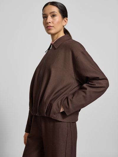 Modelka nosi Blazer mit Reißverschluss Modell 'Jelani' von OPUS, brązowy, materiał z domieszką wiskozy, krój regular fit, kołnierz koszulowy, zamek, marszczenia, długość tyłu w rozmiarze 36: 56 cm, szerokość w rozmiarze 36: 55 cm, długość rękawa w rozmiarze 36: 55 cm, widok całej sylwetki z przodu.