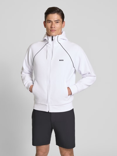 Männermodel trägt Regular Fit Sweatjacke aus Baumwoll-Mix Modell 'SAGGY' von BOSS Green in Weiß, unifarben, mit Stehkragen, Ganzkörperansicht von vorne.