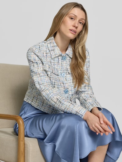 Frauenmodel trägt Regular Fit Blazer in Bouclé-Optik von Rich & Royal, Material-Mix mit Woll-Anteil, Umlegekragen, Knopfleiste, Pattentaschen, in soften Blau- und Cremetönen mit strukturierter Textur, Ganzkörperansicht von vorne.