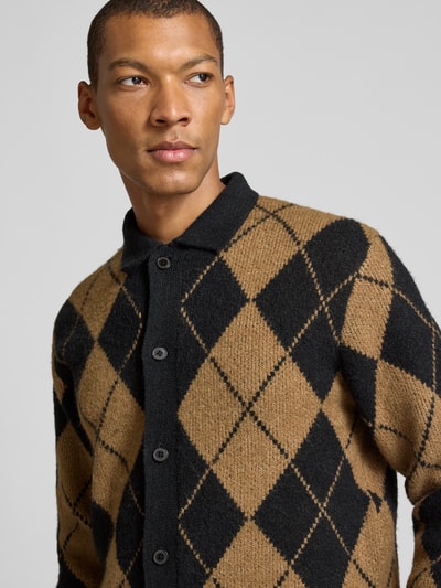 Męski model nosi Slim Fit kardigan rozpinany z dodatkiem wełny Model 'Simon' od JACK & JONES premium, elastyczna mieszanka materiałów, wykładany kołnierz, imitacja dzianiny, listwa guzikowa, kolor beżowo-czarny w romby, zbliżenie na górną część ciała