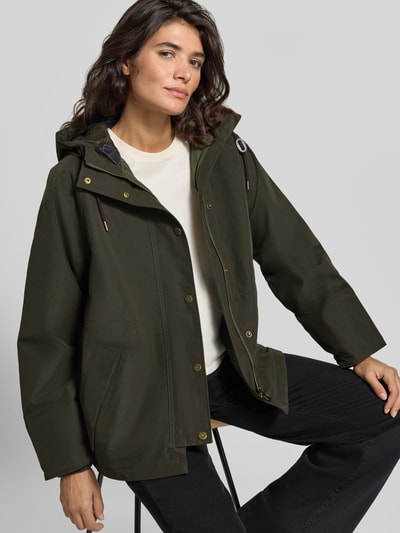 Frauenmodel trägt Loose Fit Funktionsjacke mit Kapuze Modell 'HESTER WATERPROOF' von Barbour, olivgrün, matter Stoff, Ganzkörperansicht von vorne, Damen Funktionsjacke von Barbour.