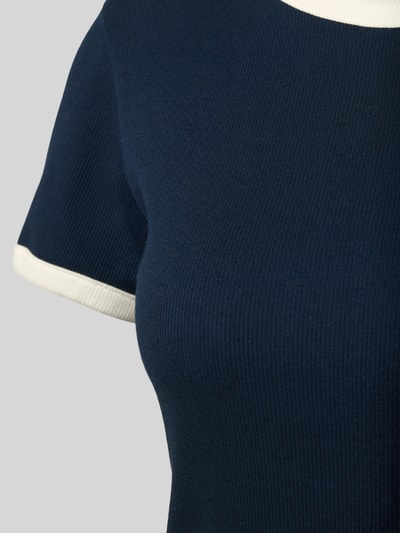 Vrouwenmodel draagt Slim Fit T-shirt uit katoenmix van Tommy Hilfiger, effen kleuren, tweekleurige look, fijnrib, logopatch, detailopname bovenlichaam.
