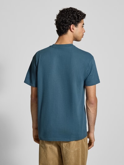 Männermodel trägt T-Shirt mit Label-Stitching von Carhartt Work In Progress aus Reine Baumwolle, Regular-Fit, Rückenlänge 74 cm, Ganzkörperansicht Rückansicht.
