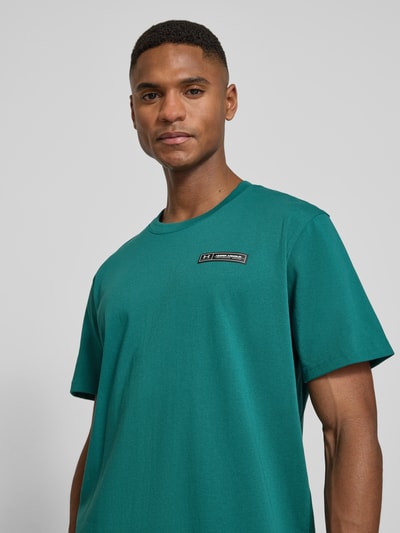 Männermodel trägt Regular Fit T-Shirt mit Logo-Applikation von Under Armour in Grün, Baumwoll-Mix, Rundhalsausschnitt, Nahaufnahme Oberkörper.