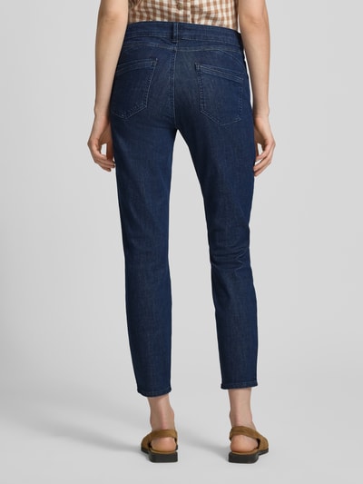 Frauenmodel trägt Slim Fit Jeans aus Baumwoll-Mix Modell 'SHAKIRA' von Brax in Dunkelblau, Denim-Optik, Label-Patch, Gürtelschlaufen, Knopf und verdeckter Reißverschluss, Ganzkörperansicht Rückansicht.