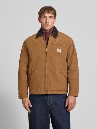 Männermodel trägt Blouson mit Brusttasche Modell 'DETROIT' von Carhartt Work In Progress in Braun mit Cord-Kragen, Ganzkörperansicht von vorne. Regular Fit, Reißverschluss, Label-Patch, seitliche Eingrifftaschen, Herren Blouson, strukturierte Oberfläche.