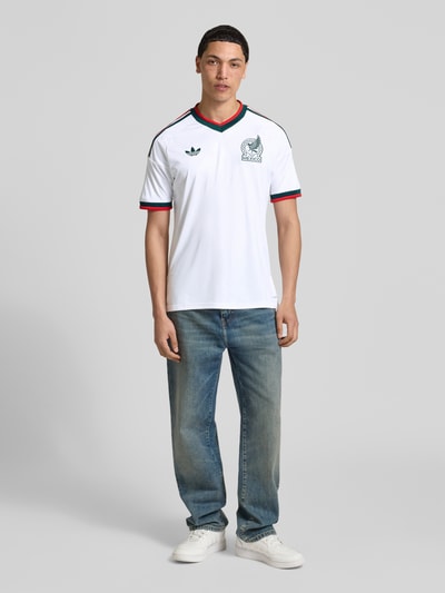 Männermodel trägt Auswärtstrikot Mexico 2026 von adidas Sportswear, Slim Fit, mehrfarbig, Logo und Verbandsapplikation, Ganzkörperansicht von vorne.