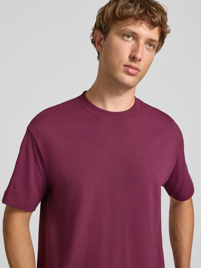 Männermodel trägt Relaxed Fit T-Shirt aus reiner Baumwolle von Marc O'Polo DENIM in Dunkelrot, glatte Textur, Nahaufnahme Oberkörper.