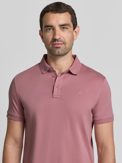Mannemodel draagt Slim Fit Poloshirt uit biologisch katoen model 'Primo' van JOOP! collectie in oudroze met labelstitching, knoopsluiting, context heren poloshirt biologisch katoen slim fit ruglengte maat M 70 cm, nahaufnahme bovenlichaam.