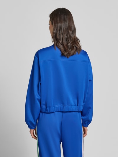 Frauenmodel trägt blaue Sweatjacke mit Kontraststreifen Modell 'Brooklynn' von Lollys Laundry, Material-Mix, Relaxed-Fit, Stitching, Stehkragen, Knopfleiste, Ganzkörperansicht Rückansicht.