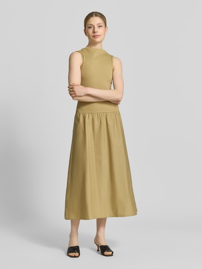 Frauenmodel trägt Midikleid mit U-Boot-Ausschnitt Modell 'VALVIN' von Mango, Baumwoll-Mix, taillierter Schnitt, beige, Ganzkörperansicht von vorne.