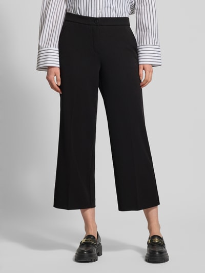 Frauenmodel trägt Hose mit verkürzter Passform Modell 'Hillda-650' von STEHMANN, schwarz, Material-Mix mit Stretch-Anteil, Ganzkörperansicht von vorne.