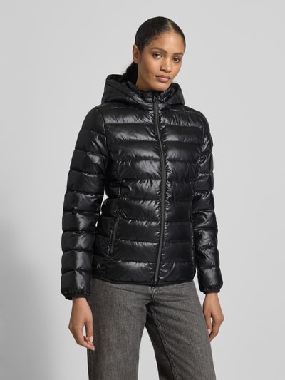 Frauenmodel trägt Jacke mit Kapuze von NAUTGÅRD in Schwarz, glänzende Oberfläche, lockerer Schnitt, Ganzkörperansicht von vorne.