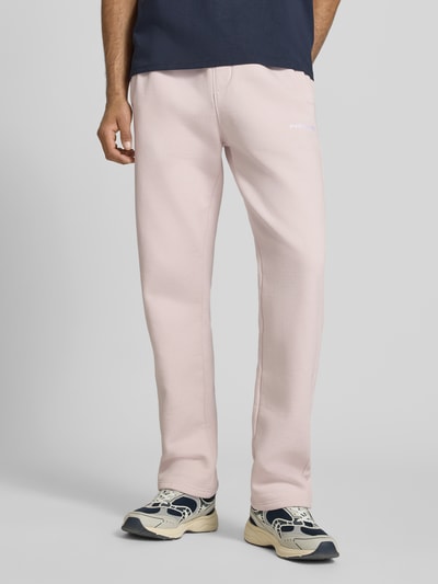 Männermodel trägt Straight Fit Sweatpants mit Logo-Stitching von Pegador aus Baumwoll-Mix in Hellrosa, Eingrifftaschen, elastischer Bund, Ganzkörperansicht von vorne.