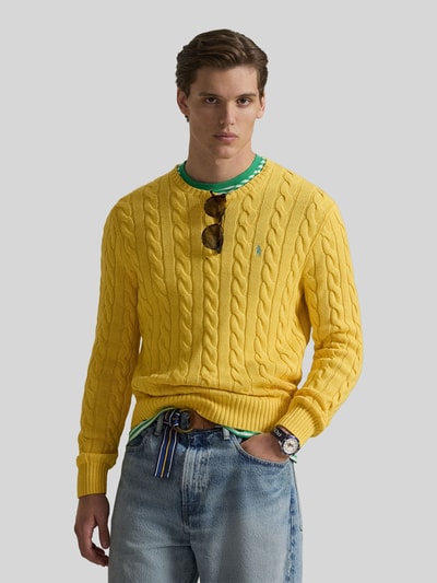 Męski model nosi Regular Fit Strickpullover aus reiner Baumwolle od Polo Ralph Lauren, żółty, splot warkoczowy, logo, dekolt okrągły, bawełna, krój regular fit, widok na górną część ciała z przodu.