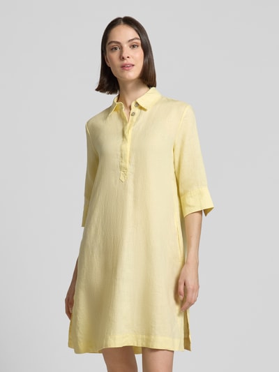 Frauenmodel trägt Knielanges Hemdblusenkleid aus Leinen mit 3/4-Arm von Christian Berg Woman in Hellgelb, A-Linie, Hemdblusenkragen, verdeckte Knopfleiste, glatte Struktur, Ganzkörperansicht von vorne.