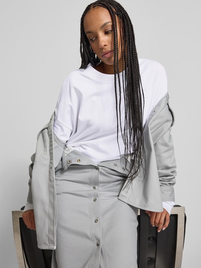 Frauenmodel trägt Oversized Longsleeve aus Baumwolle von black palms in Weiß, Damen Longsleeve, oversized, Rundhalsausschnitt, elastische Ärmelabschlüsse, Rückenlänge 79 cm bei Größe S, Nahaufnahme Oberkörper.
