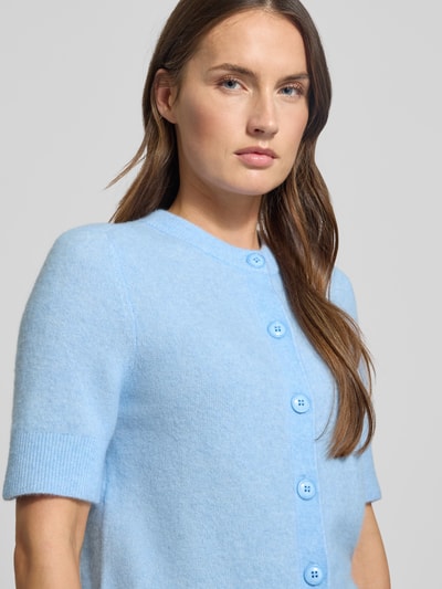 Frauenmodel trägt Strickjacke mit Knopfleiste Modell 'NOURA' von Samsøe Samsøe, hellblauer Woll-Alpaka-Mix mit Stretch-Anteil, Nahaufnahme Oberkörper.