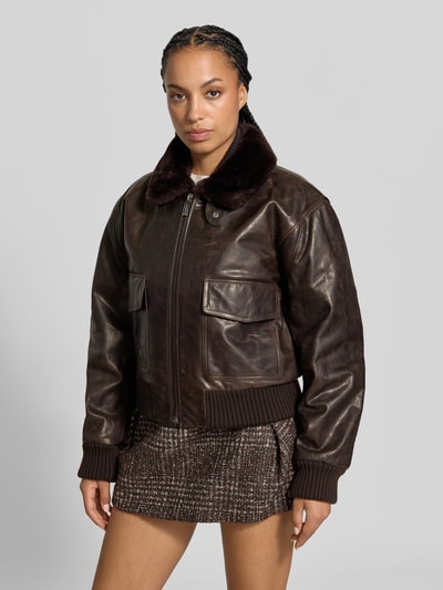Frauenmodel trägt Lederjacke mit Umlegekragen von Victoria Beckham aus echtem Leder in Dunkelbraun mit Reißverschluss und aufgesetzten Taschen, Relaxed Fit, strukturierte Oberfläche, Ganzkörperansicht von vorne.