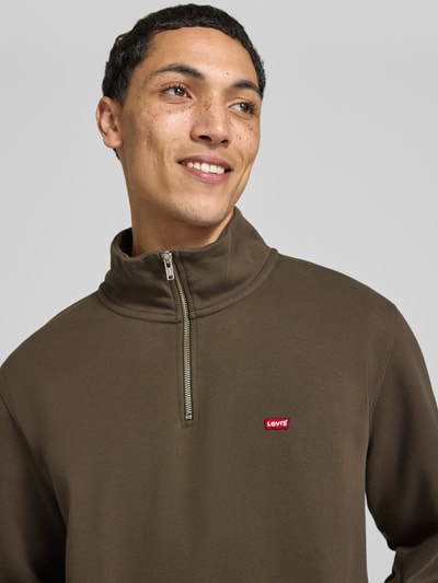 Männermodel trägt Regular Fit Troyer aus reiner Baumwolle von Levi's®, olivgrün, glatte Struktur, Levi’s-Logo, Nahaufnahme Oberkörper. Herren Troyer von Levi's®.