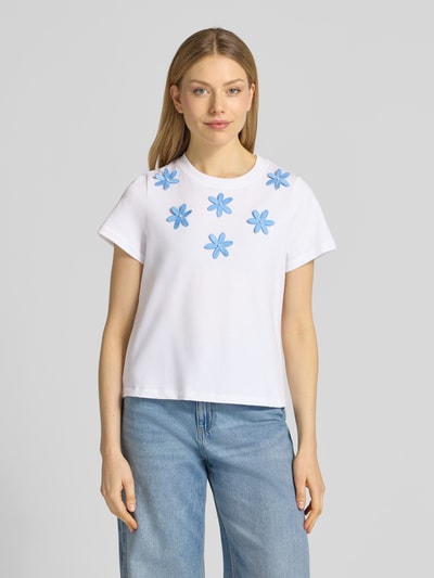 Kobiece modelka nosi damski t-shirt z haftami i perłami od Rich & Royal, czysta bawełna, krój regular fit, okrągły dekolt, długość tyłu w rozmiarze S: 54 cm, widok całej sylwetki z przodu.