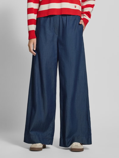 Männermodel trägt Wide Leg Tencel Hose mit Gummibund von Christian Berg Woman, Lyocell-bawełna, szerokość w rozmiarze 36: 41 cm, długość wewnętrzna nogawki 77 cm, krój wide leg, zdjęcie całej sylwetki z przodu.