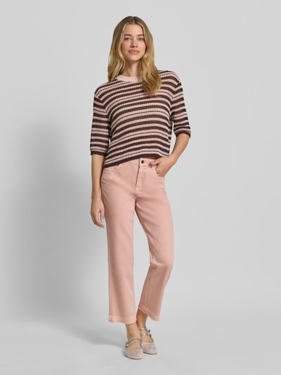 Kobiece model prezentuje Feminine Fit Jeans mit Fransen und Eingrifftaschen von Marc Cain z mieszanki bawełny i elastanu, kolor jasnoróżowy, wpuszczane kieszenie, frędzle na dole, szerokość w rozmiarze 36: 38 cm, długość wewnętrzna nogawki w rozmiarze 36: 70 cm, widok całej sylwetki z przodu.