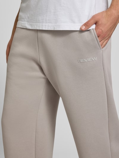 Männermodel trägt Regular Fit Sweatpants mit Gesäßtasche von REVIEW in Beige, Baumwoll-Mix, elastischer Bund, Nahaufnahme Oberkörper.