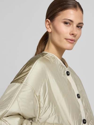 Frauenmodel trägt Steppjacke mit aufgesetzten Eingrifftaschen und Kapuze von Blonde No. 8 in hellem Beige mit Knopfverschluss, Nahaufnahme Oberkörper