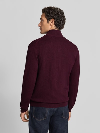 Männermodel trägt Regular Fit Pullover aus reiner Wolle von GANT in Bordeaux, einfarbig, Strickstruktur, gerippte Abschlüsse, Ganzkörperansicht Rückansicht.