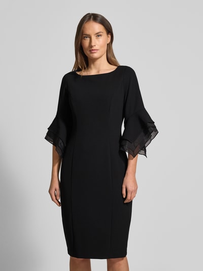 Frauenmodel trägt knielanges Cocktailkleid mit Trompetenärmeln von Adrianna Papell, schwarzer Material-Mix mit Stretch-Anteil, gerader Schnitt, Rundhalsausschnitt, Ganzkörperansicht von vorne.