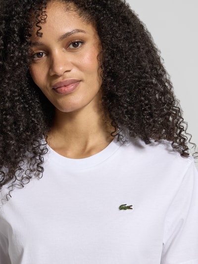 Frauenmodel trägt Relaxed Fit T-Shirt aus reiner Baumwolle von Lacoste Sport, weiß unifarben, Logo-Stitching, Nahaufnahme Oberkörper.