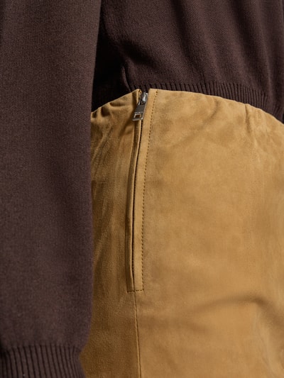 Frauenmodel trägt Minirock aus echtem Ziegenvelours von ROTATE in Beige, samtige Textur, sichtbarer Reißverschluss, Nahaufnahme Oberkörper.