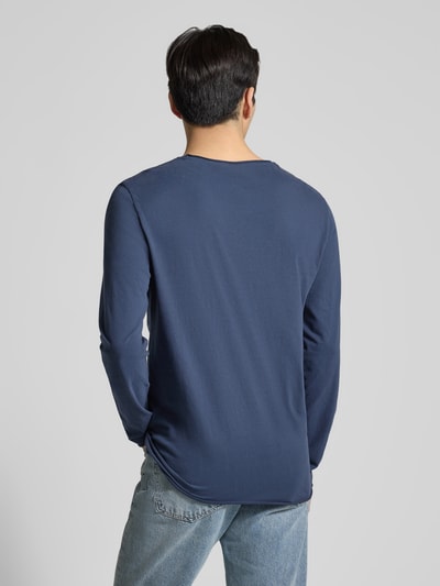 Männermodel trägt Regular Fit Langarmshirt aus reiner Baumwolle Modell 'JAAMES' von Armedangels in Dunkelblau, Ganzkörperansicht Rückansicht. Unifarbene Optik, Rollsaum an Ärmeln und Rumpf, Jersey-Textur.