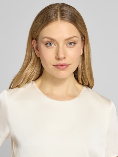 Modelka nosi Regular Fit T-Shirt mit rundhalsausschnitt von Christian Berg Cocktail, elastyczny materiał, satynowa tekstura, kolor jasny, krój regular fit, dekolt okrągły, ujęcie z przodu, zbliżenie na górną część ciała.