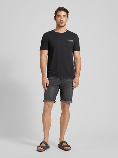 Männermodel trägt Regular Fit Jeans Bermudas aus Baumwoll-Mix von Tom Tailor in dunkler Denim-Optik mit Label Patch und 5-Pocket-Design, Ganzkörperansicht von vorne.