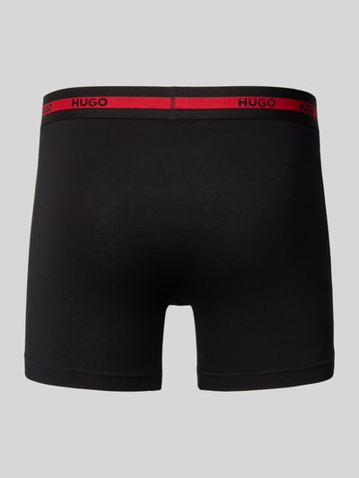 Männermodel trägt Boxershorts mit elastischem Logo-Bund im 3er-Pack von HUGO, Unifarbenes-Design, Baumwoll-Elasthan-Mix, Ganzkörperansicht Rückansicht.