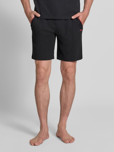 Männermodel trägt Regular Fit Sweatshorts aus Baumwoll-Mix Modell 'NOAH' von HUGO, unifarben, Label Stitching, Nahaufnahme Vorderansicht.