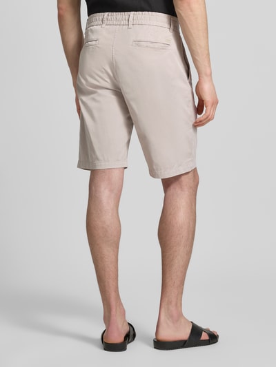 Männermodel trägt Tapered Chinoshorts aus Baumwoll-Mix von BOSS Orange, Optik: Unifarben, Materialverarbeitung: Twill, Ganzkörperansicht Rückansicht.