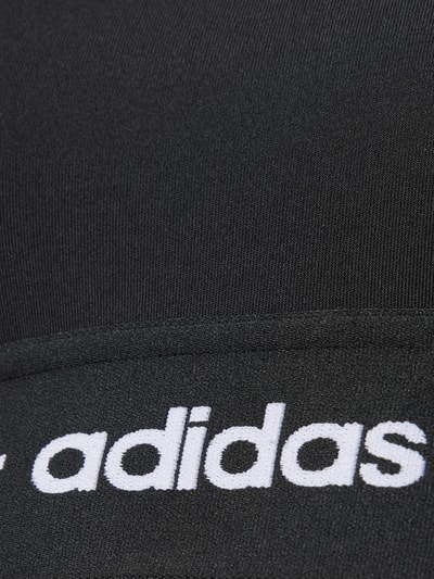 Productfoto, BH met elastische logoband van adidas Sportswear, zwart, fijne textuur, lichaamsvolgend, materiaal met stretch.