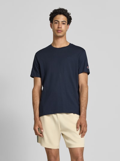 Männermodel trägt T-Shirt mit Label-Stitchings und Rundhalsausschnitt von CHAMPION, Regular-Fit, Reine Baumwolle, Herren T-Shirt, Rückenlänge bei Größe M 66 cm, Ganzkörperansicht von vorne.