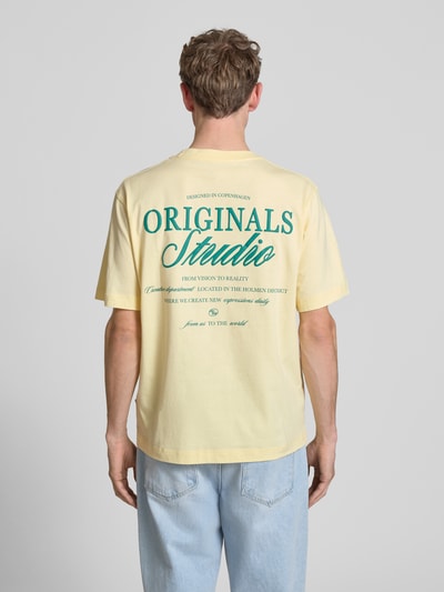 Männermodel trägt T-Shirt mit Label-Print von Jack & Jones in Gelb aus Reine Baumwolle, Relaxed-Fit, Rückenlänge 70 cm, Ganzkörperansicht Rückansicht.